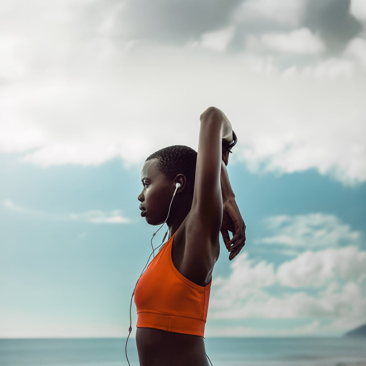 Woman in orange sports top stretching outdoors